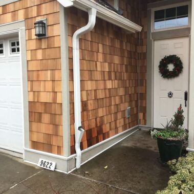 3x4 gutter cleanout system with max flow outlet installed on cedar shake siding, featuring seamless integration with traditional home design