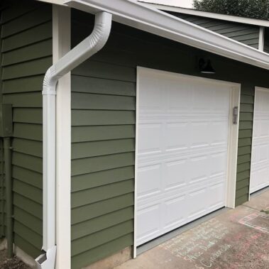 3x4 K-style gutter with matching downspout installed on green siding, showcasing seamless integration and efficient water management for garage area