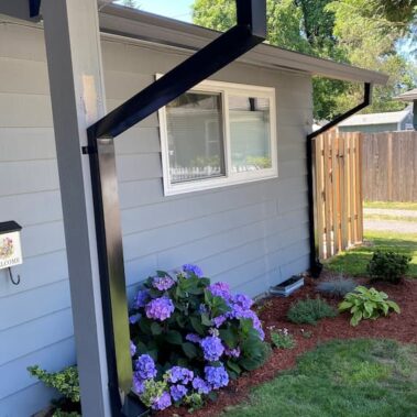 Professional gutter cleanout system with large black downspout outlet installed on white house siding, making maintenance easy and preventing clogs