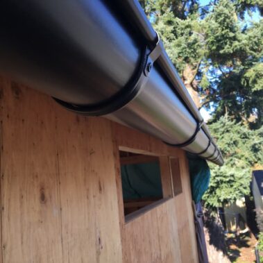 Royal Gutters' sleek black half-round gutter with sturdy external hangers, expertly installed on Portland home. Durability meets style. 503-558-8700