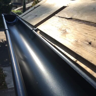 Royal Gutters' sleek black half-round gutter with durable external hangers. Professional Portland installation for maximum durability. 503-558-8700