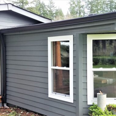 Black K-Style gutter with max flow outlet and cleanout installed on gray Portland home, showcasing efficient water management and easy maintenance features