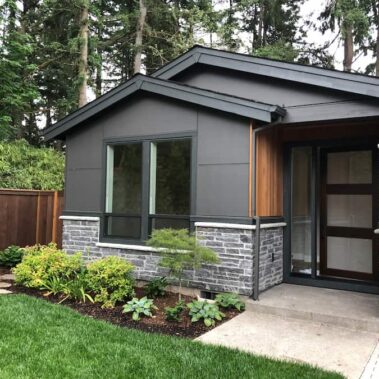 Modern black K-style gutter with square downspout on contemporary Portland home, matching dark gray exterior with stone and wood accents