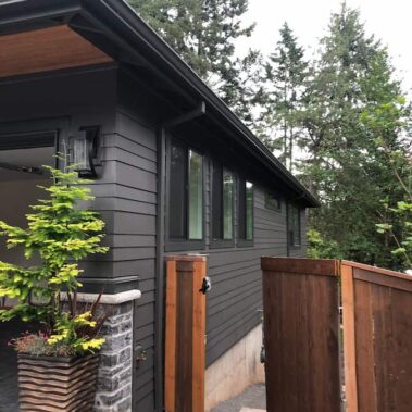 Black K-Style gutter with square downspout on modern dark gray house, featuring clean lines and minimalist design for contemporary Portland homes