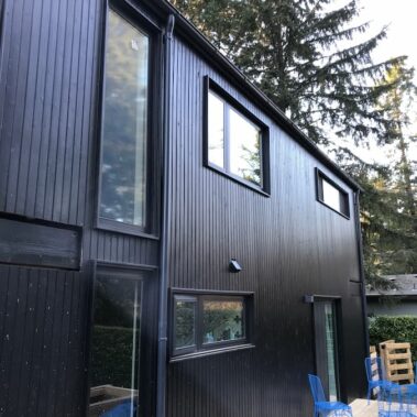 Royal Gutters' black round downspout installation - modern design for contemporary Portland homes. Professional service: 503-558-8700