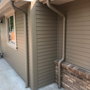 Royal Gutters' black round downspout with K-style connection - professional corner installation by Portland experts. Call 503-558-8700
