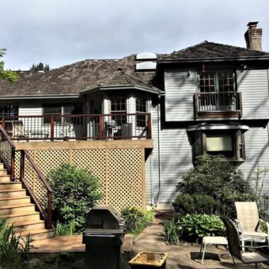 Colonial blue gutter system professionally installed on two-story white siding home, featuring multi-level drainage and architectural integration