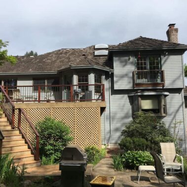 Multi-level craftsman home gutter system with square downspouts, featuring coordinated installation around deck and siding for complete water management