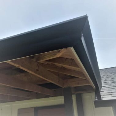 Craftsman brown box-bottom gutter installed on exposed wooden rafters, showcasing seamless integration with porch overhang and asphalt shingle roof