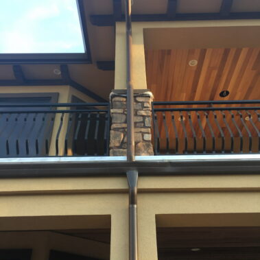 Royal Gutters' brown-black round downspout with Max Flow technology - elegant solution for custom homes in Portland. Call 503-558-8700