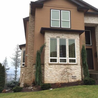 Modern two-story house with brown box-bottom gutters seamlessly integrated with brown siding and stone veneer, showcasing aesthetic gutter solutions