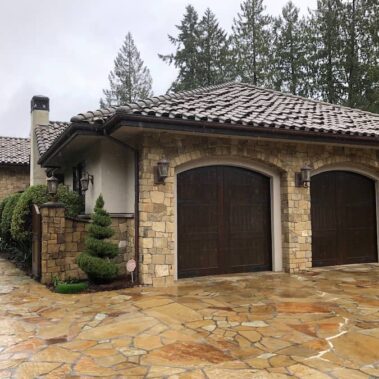 Royal Gutters' brown half-round gutters and round downspouts on luxury Portland home. Seamless integration with stone and tile. 503-558-8700