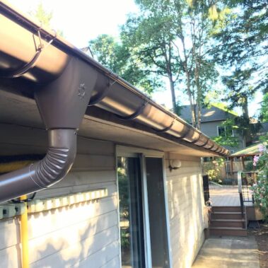 Royal Gutters' brown half-round system with external brackets, round downspout, and large outlet. Expert Portland installation. 503-558-8700