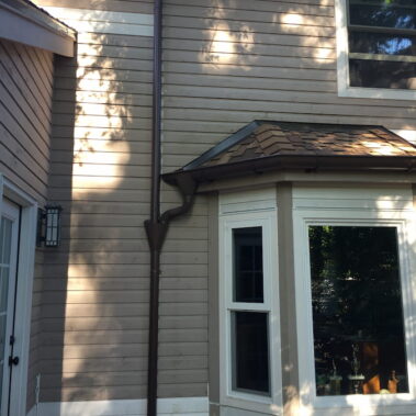 Royal Gutters' brown half-round system with custom funnel collector and round downspout, expertly installed in Portland. 503-558-8700