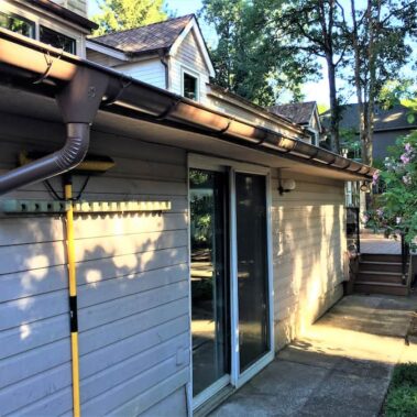 Royal Gutters' brown half-round gutter system with premium large outlet and round downspout, professionally installed in Portland. 503-558-8700