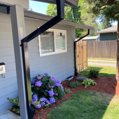 Royal Gutters' black square downspouts expertly installed on white Portland home. Seamless integration, beautiful landscaping. 503-558-8700Style Fascia Gutter