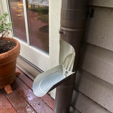 Brown round downspout with integrated cleanout system by Royal Gutters, featuring easy-access maintenance panel for efficient gutter cleaning and debris removal