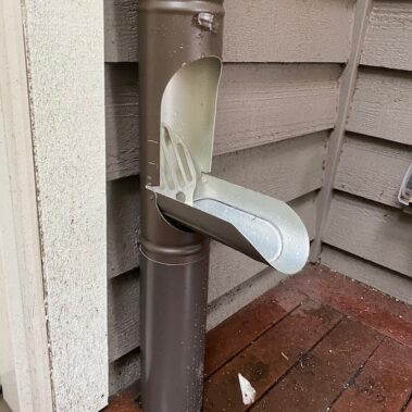 Royal Gutters seamless white gutter system on cream-colored siding, showcasing clean installation and perfect blend with lush landscaping for enhanced curb appeal