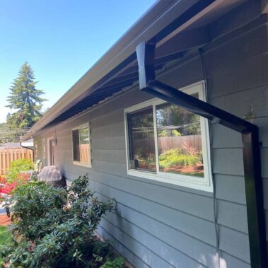 Royal Gutters' black square downspout installation - seamless integration with modern gray siding. Portland experts: 503-558-8700