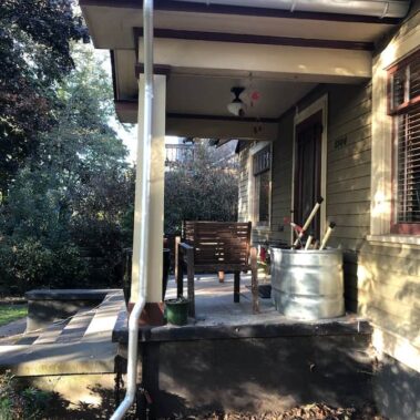 Royal Gutters' galvanized round downspout on porch - classic style, superior drainage for Portland homes. 503-558-8700