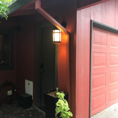 Royal Gutters' red square downspout installation with evening lighting - custom color options for Portland homes. Call 503-558-8700