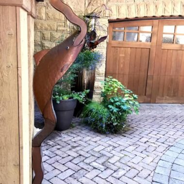 Royal Gutters Portland bronze wavy downspout installation - artistic water management for luxury homes with custom landscaping