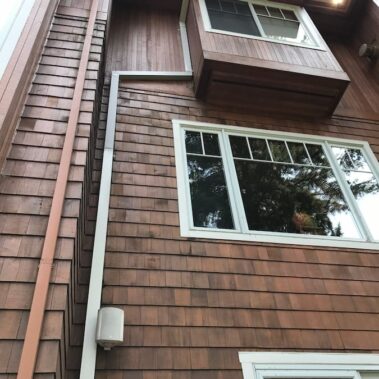 Royal Gutters' smooth square downspout on multi-level Portland wood home - seamless integration, efficient drainage. Call 503-558-8700