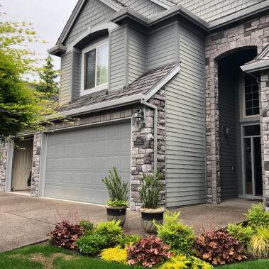 Royal Gutters' premium square downspout installation on luxury stone facade home. Expert Portland craftsmanship. Call 503-558-8700
