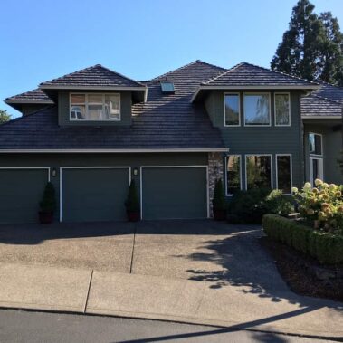 White seamless gutter and downspout installation on modern green craftsman home with stone accents and professional landscaping by Royal Gutters Portland