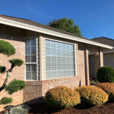 White craftsman bottom gutter seamlessly installed on brick home with professional landscaping, showcasing clean lines and curb appeal enhancement