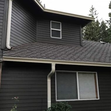 Craftsman-style house with brown box-bottom gutters installed on exposed wooden rafters, showcasing integration with porch overhang and asphalt shingle roof