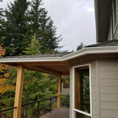 High-capacity gutter with max flow outlet installed near brick chimney, providing enhanced drainage for traditional home with landscaping