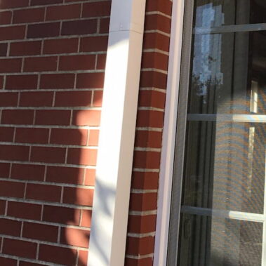 Royal Gutters' white square downspout installation on brick facade - precision crafted for Portland homes. Professional service: 503-558-8700